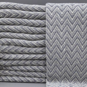 May include: A stack of gray and white chevron patterned towels with white fringe.