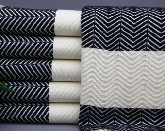 May include: A stack of black and white striped towels with a herringbone pattern. The towels are folded and arranged in a row.