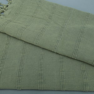 May include: A sage green striped cotton towel with fringed edges.