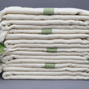 May include: A stack of eight white cotton towels with green stripes. The towels are folded and stacked neatly.