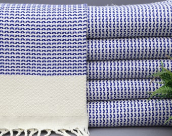 Peut inclure: Une pile de serviettes blanches avec un motif géométrique bleu. Les serviettes ont une frange en bas.