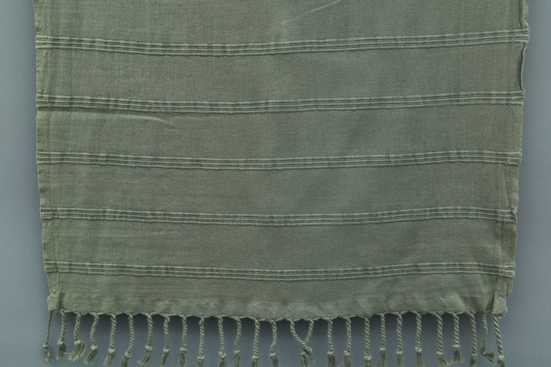 May include: A green striped cotton towel with fringe on the bottom edge.