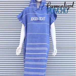 May include: A blue hooded poncho featuring white horizontal stripes and a front kangaroo pocket. The text "LOGO-TEXT" is embroidered on the chest. The garment has short sleeves and a fringed hemline at the bottom, displayed on a white mannequin.