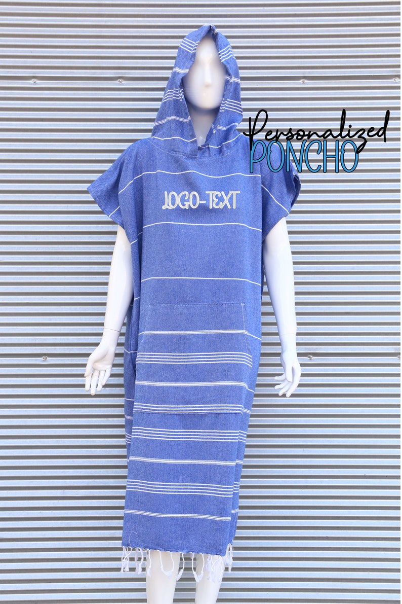 May include: A blue hooded poncho featuring white horizontal stripes and a front kangaroo pocket. The text "LOGO-TEXT" is embroidered on the chest. The garment has short sleeves and a fringed hemline at the bottom, displayed on a white mannequin.