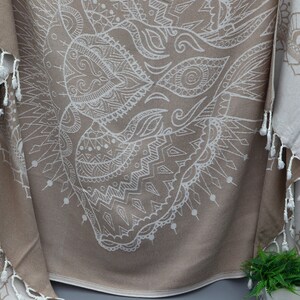 May include: A beige and white patterned throw blanket with fringe. The pattern is a large mandala design with intricate details.