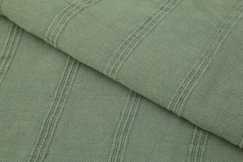 May include: Close-up of a sage green fabric with a ribbed texture. The fabric has vertical stripes that are slightly raised.