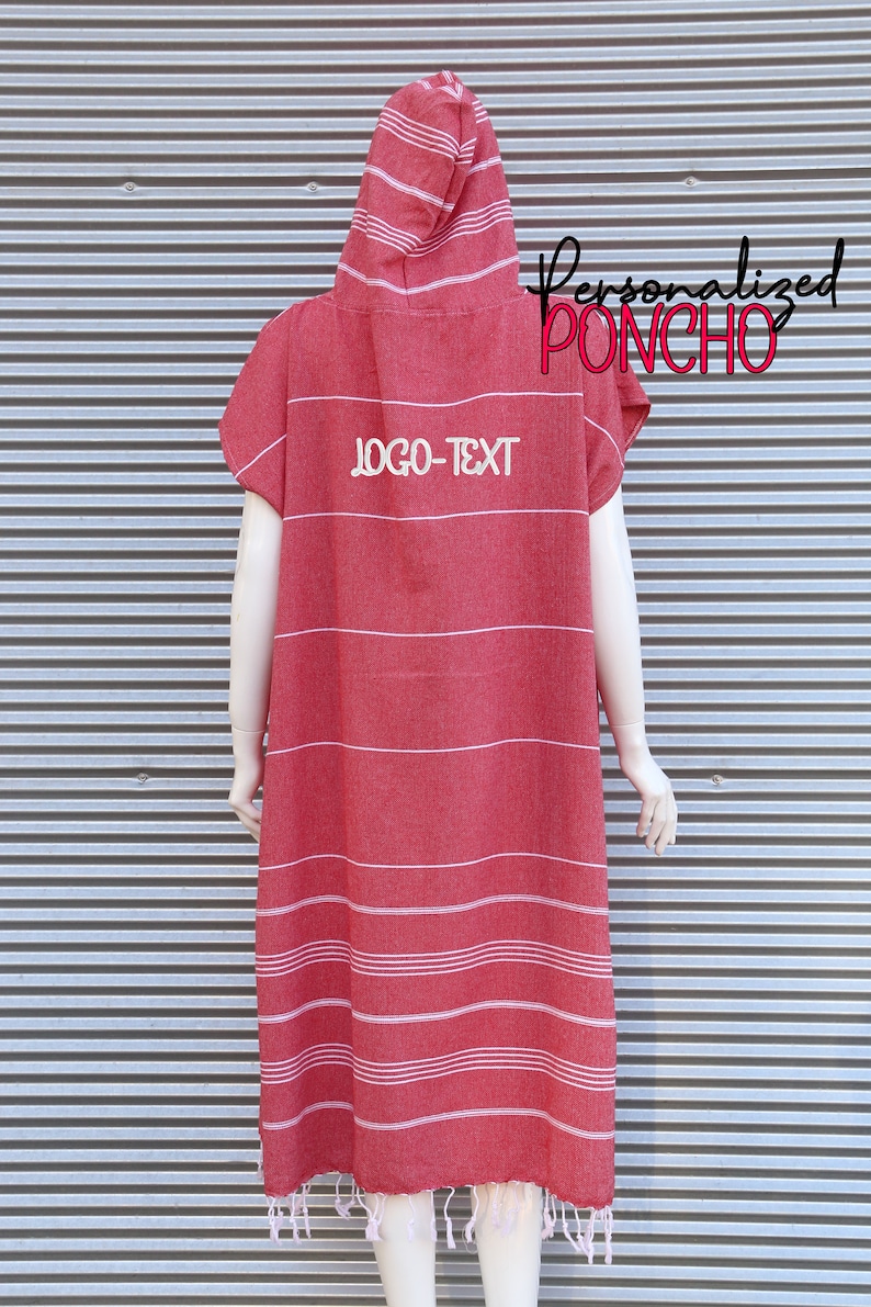 May include: A red hooded poncho featuring thin white horizontal stripes and white fringe at the bottom hem. The garment displays the text "LOGO-TEXT" in white on the upper back, with "Personalized PONCHO" written in black and red script nearby.