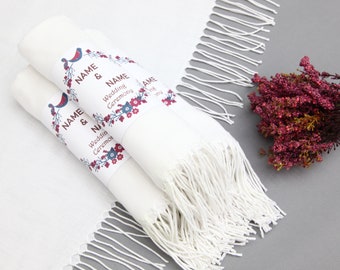 Könnte beinhalten: Zwei weiße Hochzeitsschals mit Fransen, aufgerollt und mit einem Band gebunden. Das Band hat ein florales Design mit Vögeln und dem Text "NAME & NAME Hochzeitszeremonie".