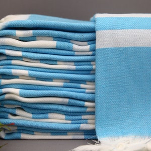 May include: A stack of light blue and white striped towels with fringed edges. The towels are folded neatly and are made of a soft, absorbent material.