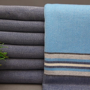 May include: A stack of dark blue towels with a light blue towel with white and gray stripes on the right side.
