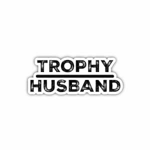 May include: Black and white graphic text that reads "TROPHY HUSBAND" with a line under the word "TROPHY".