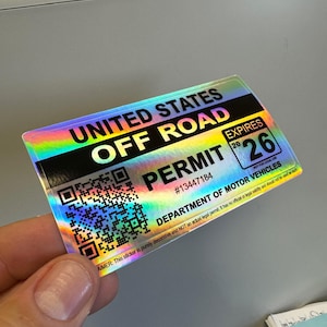 May include: A holographic sticker with a black background and white text that reads "United States Off Road Permit" with a QR code and the text "#13447184" and "Expires 20 26" with the text "Department of Motor Vehicles" and a disclaimer that reads "This sticker is purely decorative and NOT an actual legal permit. It has no official or legal validity and should not be used as such."