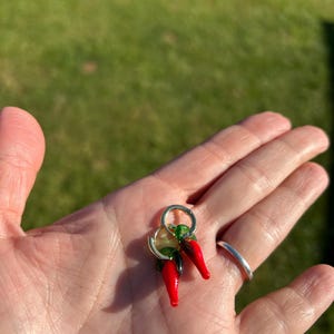 Puede incluir: Un par de pendientes de aro de oro con abalorios de chile rojo y verde de vidrio.