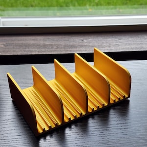 May include: A yellow plastic organizer with five compartments. The organizer is designed to hold small items, such as pens, pencils, or other office supplies.