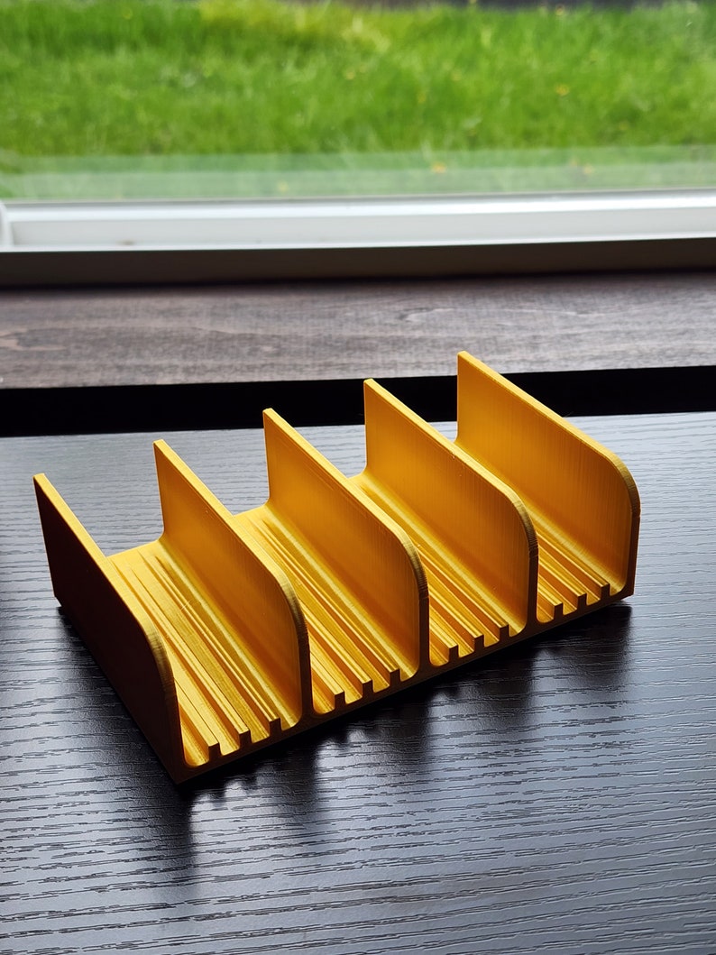 May include: A yellow plastic organizer with five compartments. The organizer is designed to hold small items, such as pens, pencils, or other office supplies.