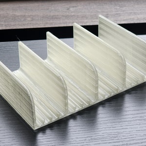 May include: A white plastic organizer with five compartments, designed to hold small items like utensils or craft supplies.