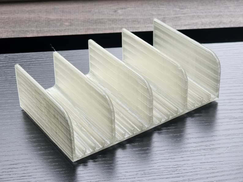May include: A white plastic organizer with five compartments, designed to hold small items like utensils or craft supplies.