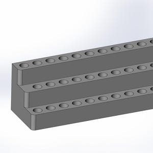 May include: A grey, stepped organiser with three tiers, each with evenly spaced circular holes. The design is simple and functional, likely for holding small items like pens or tools. The organiser is made of a solid, matte material.