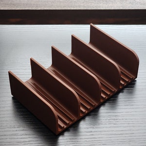 May include: A brown plastic organizer with five slots for storing items. The organizer has a textured surface and is designed to hold items upright.
