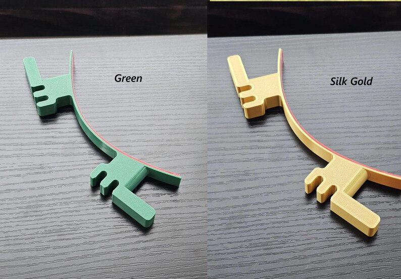 May include: Two plastic hair clips, one green and one gold, with a red stripe on the inside of the curve. The clips are shaped like a hand with three fingers.
