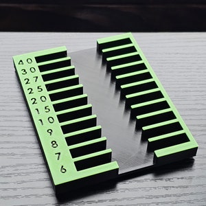 May include: A green and black plastic organizer with 15 slots numbered 40 to 76. The organizer is designed to hold small items, such as tools or craft supplies.
