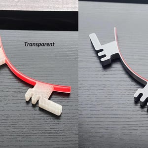 May include: Two 3D printed plastic parts, one transparent and one gray, with a red line running along the edge of each. The text "Transparent" is above the transparent part and the text "Gray" is above the gray part.