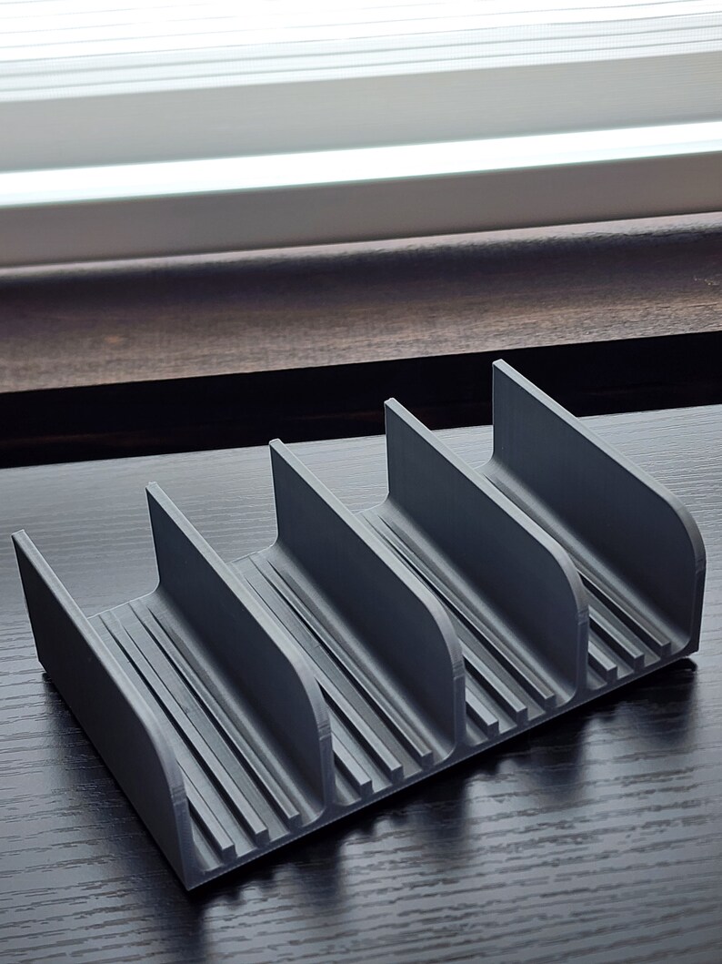 May include: A gray plastic organizer with four compartments. The organizer has a ribbed texture and is designed to hold small items.