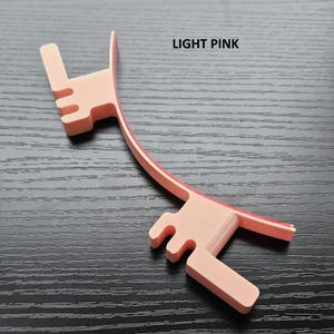 May include: Light pink plastic headband with a curved design and a small, raised section on each end. The text "LIGHT PINK" is printed on the image.