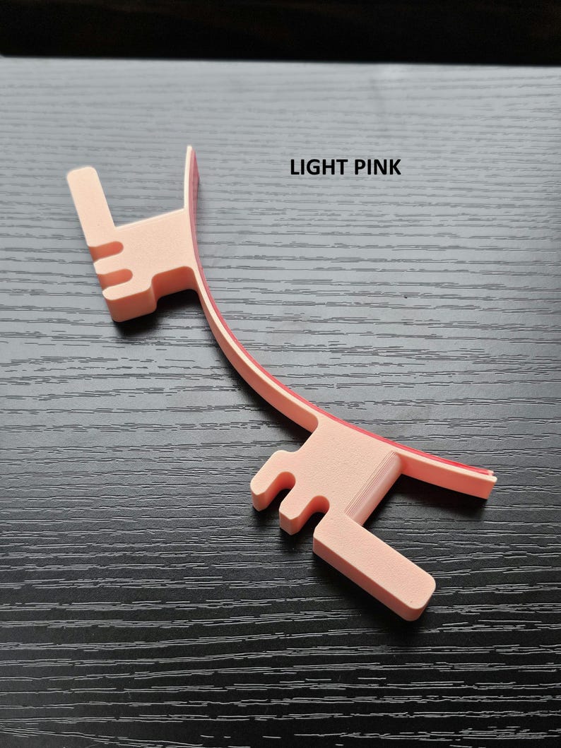 May include: Light pink plastic headband with a curved design and a small, raised section on each end. The text "LIGHT PINK" is printed on the image.