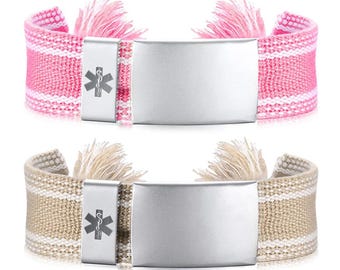 May include: Two medical alert bracelets. One is pink with white stripes, the other is beige with white stripes. Both have a silver plate and a medical symbol. Each bracelet has a tassel on each end.