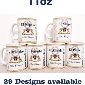 May include: White ceramic mugs with various Spanish phrases like "El Esposo" and "El Amigo" printed on them. Each mug has a Modelo beer label design. The text "11oz" and "29 Designs available" are also visible.