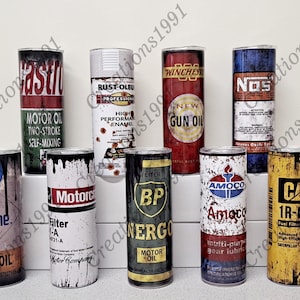 May include: Nine different vintage-style metal can designs printed on stainless steel tumblers. The designs feature various brands of motor oil, gun oil, gear lubricant, and fuel filters. The tumblers are all the same size and shape, and they are arranged in a row on a white surface.