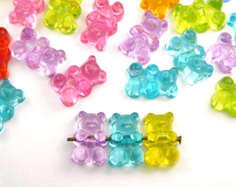 May include: Assortment of colorful gummy bear charms in various colors, including red, orange, yellow, green, blue, and purple. The charms are arranged on a white surface.