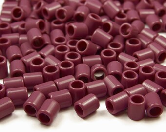 Puede incluir: Un montón grande de pequeñas cuentas de plástico de color morado oscuro. Las cuentas son de forma cilíndrica con un agujero en el centro.