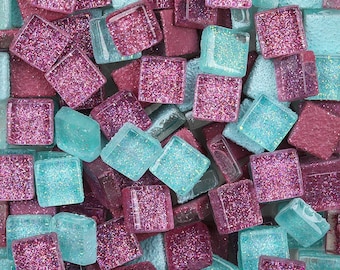 Puede incluir: Primer plano de una colección de pequeñas baldosas de mosaico cuadradas. Las baldosas son una mezcla de azul claro y rosa con detalles de purpurina.