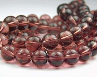 May include: A strand of round, translucent, faceted glass beads in a deep burgundy colour. The beads have a slight shimmer and are strung on a clear thread.