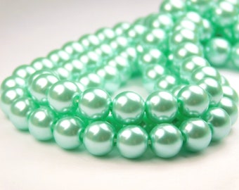 May include: A strand of light green pearl beads. The pearls are round and have a smooth, glossy finish.