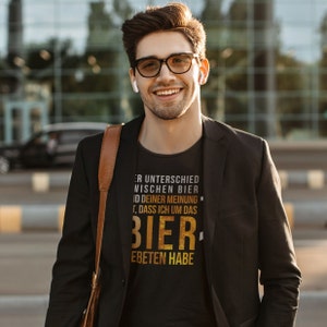 Könnte beinhalten: Ein schwarzes T-Shirt mit einer goldenen Grafik, auf der "ER UNTERSCHIED NISCHEN BIER ID DEINER MEINUNG T, DASS ICH UM DAS BIER EBETEN HABE" steht.