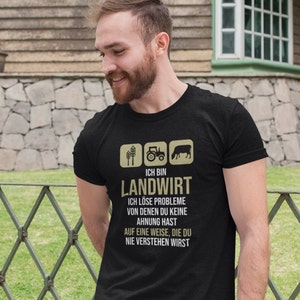 Puede incluir: Una camiseta negra con un gráfico de iconos de granja y el texto "ICH BIN LANDWIRT ICH LÖSE PROBLEME VON DENEN DU KEINE AHNUNG HAST AUF EINE WEISE, DIE DU NIE VERSTEHEN WIRST"