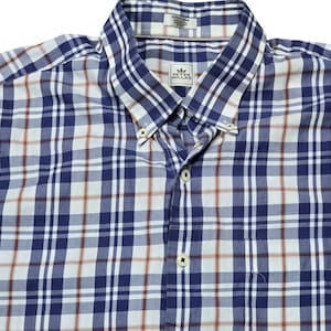 以下が含まれることがあります： 青、白、赤のチェック柄のボタンダウンシャツ。ボタンダウンカラー、胸ポケット、Peter Millarのロゴが特徴です。軽量で快適な生地で作られています。クラシックなデザインです。
