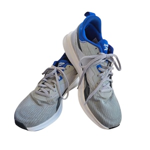 Op de afbeelding: Grijze en blauwe sportschoenen met witte zolen. De schoenen hebben grijze veters en het Reebok-logo is zichtbaar. Ze zijn ontworpen voor hardlopen en andere sportieve activiteiten.