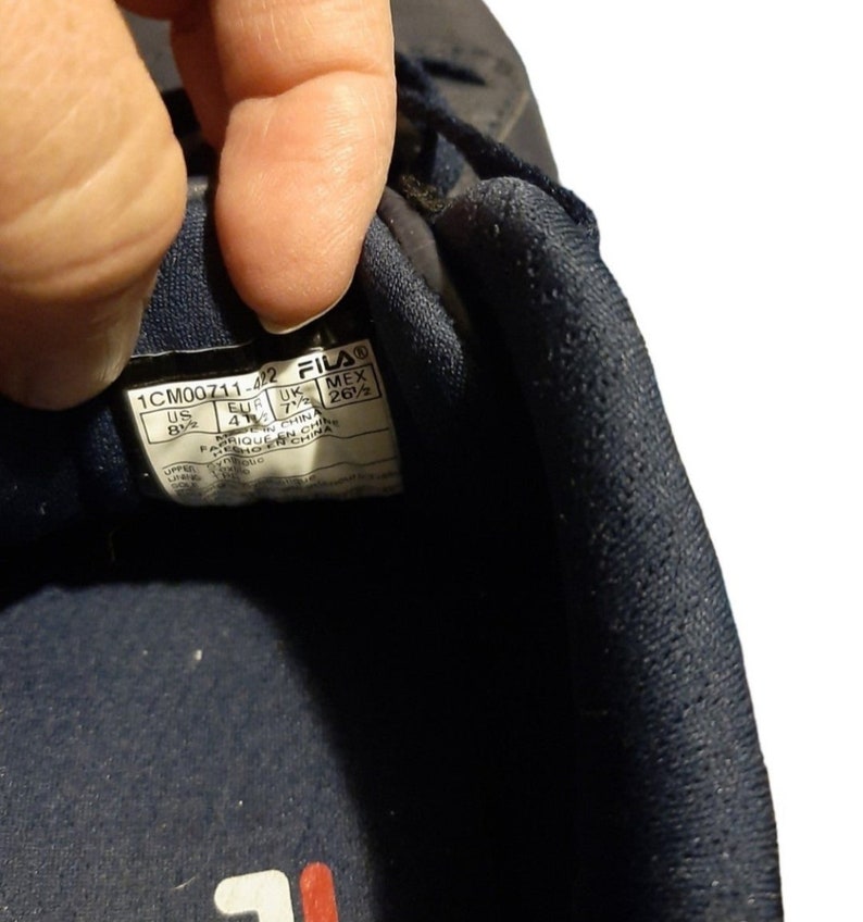 May include: Close-up of a navy blue Fila athletic shoe. The shoe's interior label displays size information: US 8.5, EUR 41, UK 7.5, and MEX 26.5. The shoe is made in China.