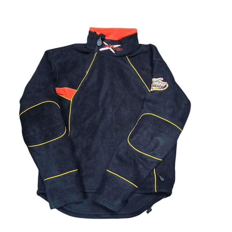 May include: Black fleece jacket with a high collar and a zip closure. The jacket features orange and yellow accents, including a logo patch on the sleeve and embroidered details. The jacket has a drawstring at the bottom.