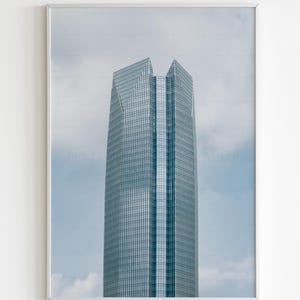 May include: A vertical wall art print featuring a tall, modern skyscraper with a glass facade and a geometric, multi-faceted top section. The building is set against a cloudy sky. The text Emily Terranova Prints appears at the top.