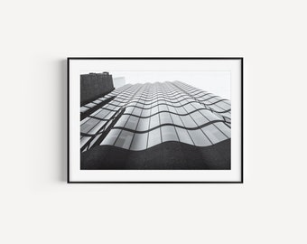 May include: Black and white photograph of a modern skyscraper with a wavy glass facade.