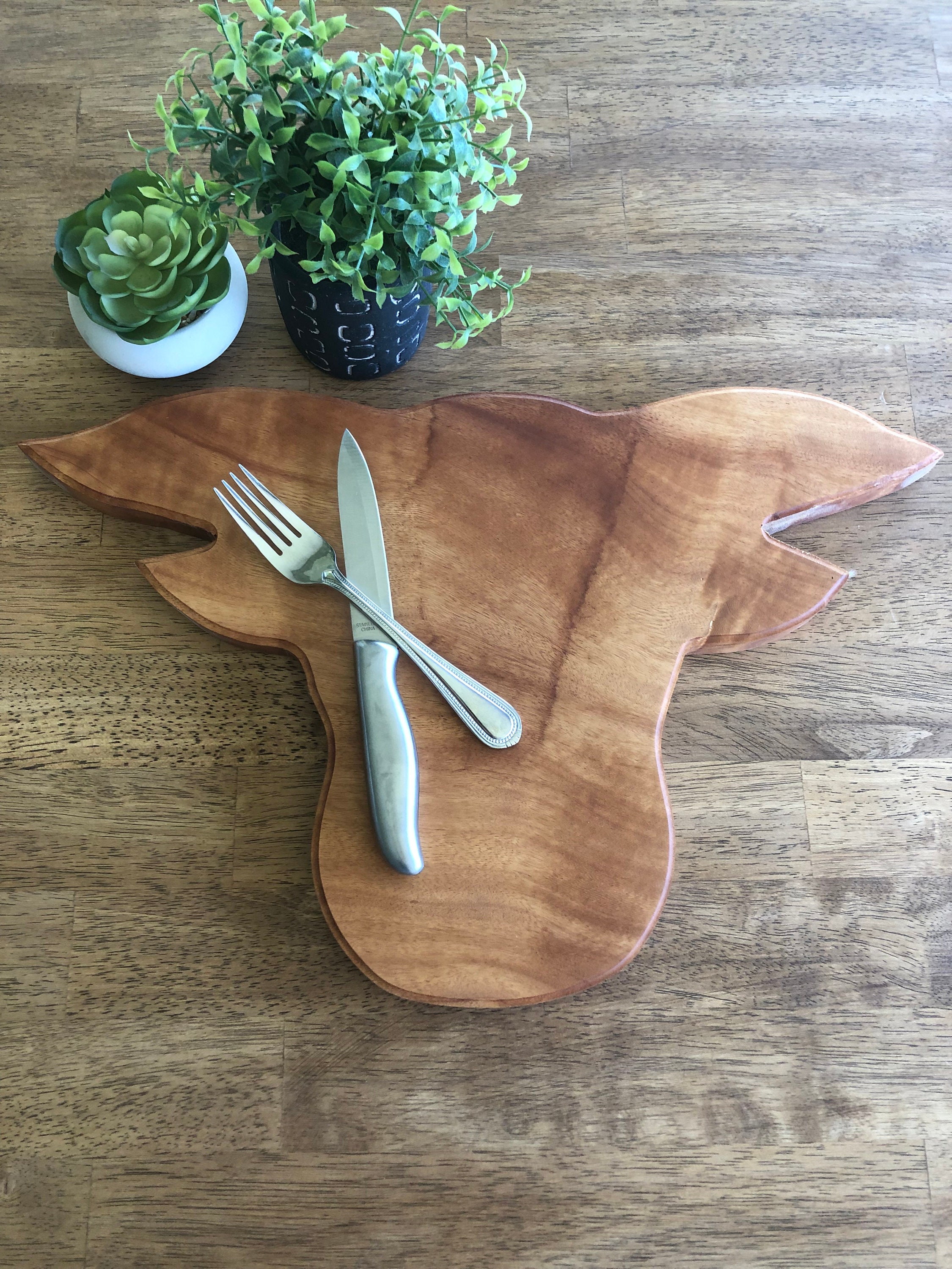 4 halved avocados sit on a cute cow-shaped wooden cutting board. A