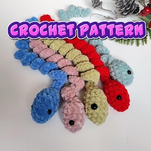 May include: Crochet pattern for a colorful set of five crocheted snake toys. The snakes are blue, pink, green, red, and light blue. The snakes are curled up and have black eyes.