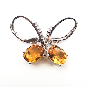 Puede incluir: Pendientes de mariposa de plata con piedras ovaladas de color naranja y detalles de circonita cúbica transparente.