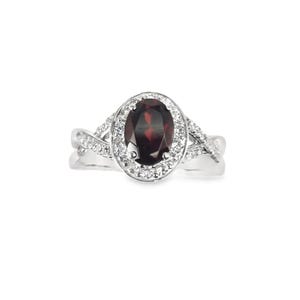 Puede incluir: Un anillo de plata con una piedra ovalada roja rodeada por un halo de piedras blancas más pequeñas. La banda está retorcida y presenta piedras blancas adicionales.