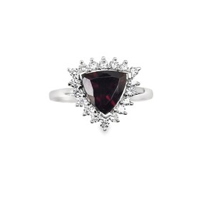 Puede incluir: Un anillo de plata con una piedra roja triangular rodeada por un halo de piedras blancas más pequeñas.
